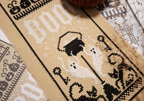 Halloween themed cross stitch on black and white threads on tan coloured aida fabric