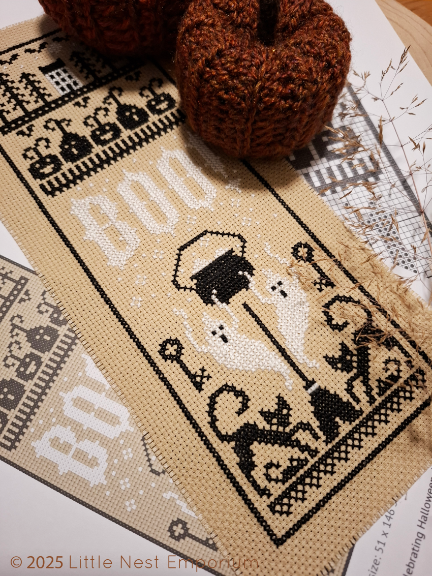 Halloween themed cross stitch on black and white threads on tan coloured aida fabric