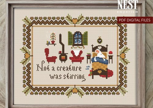 A Christmas themed cross stitch design on a cram background in a wooden frame - the cross sticth depicts a white mouse tucked up in a tiny wooden bed, in the background two red armchairs and a pot bellied stove.