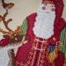 A cross stitch picture depicting a woodland santa figure in red waistcoat with green trousers. Santa pats a reindeer and a robin looks on